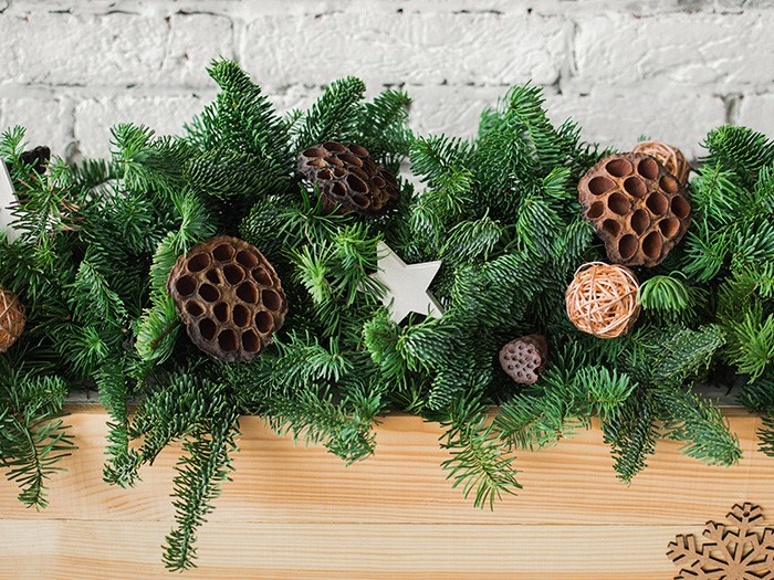 Green pine vine on wooden fireplace mantel with brown tuck in seed pods for accent 